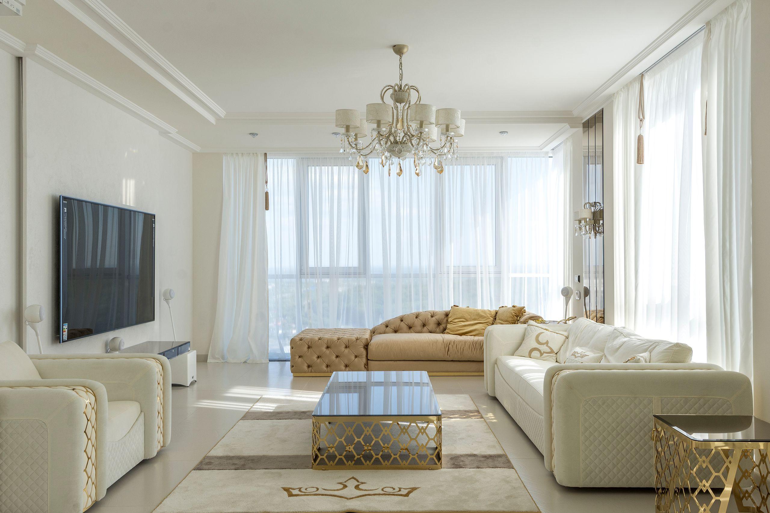 A bright, quietly furnished private lounge with tall windows, sheer curtains, and soft daylight