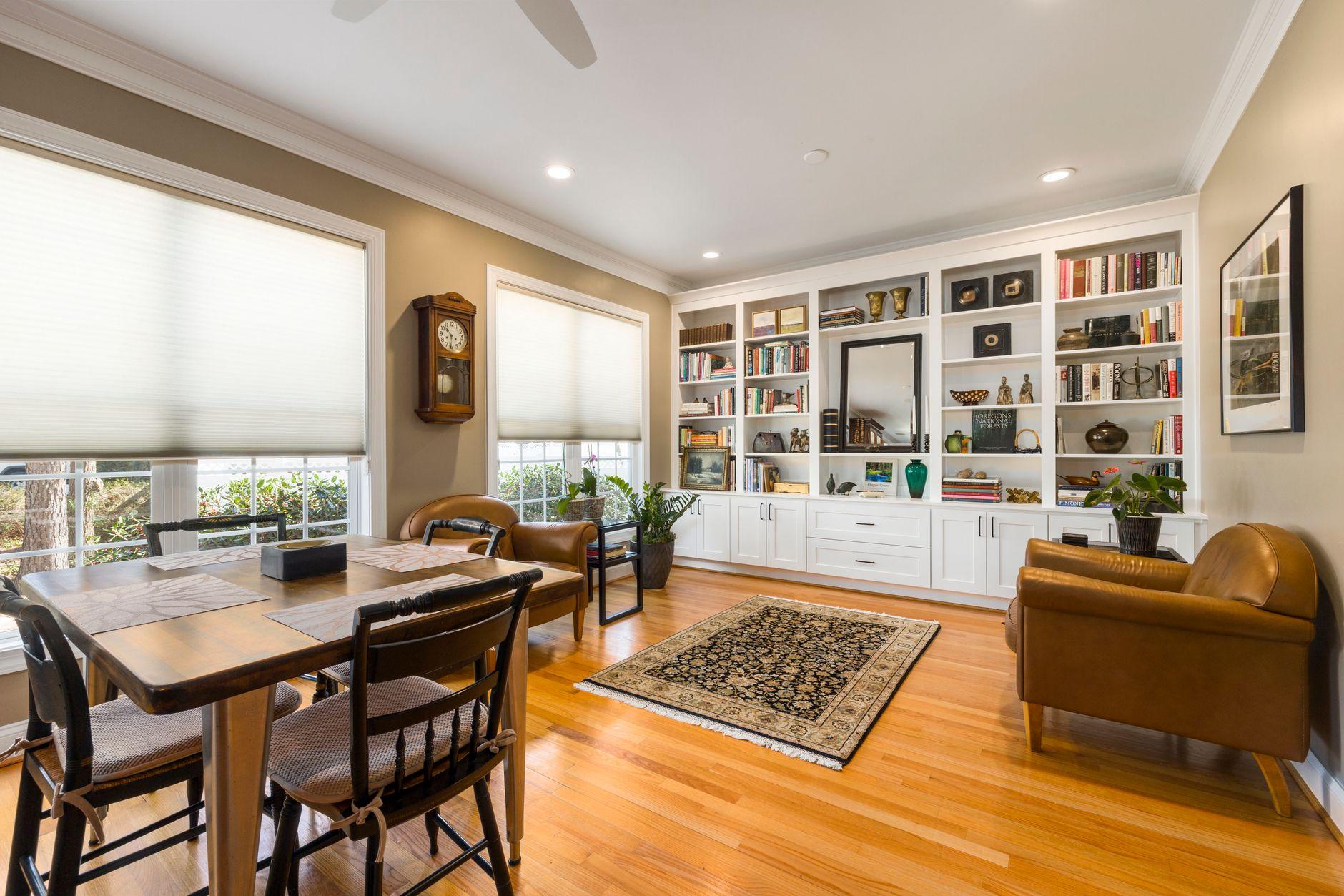 A private study with built-in bookshelves, leather armchairs, and warm daylight through tall windows