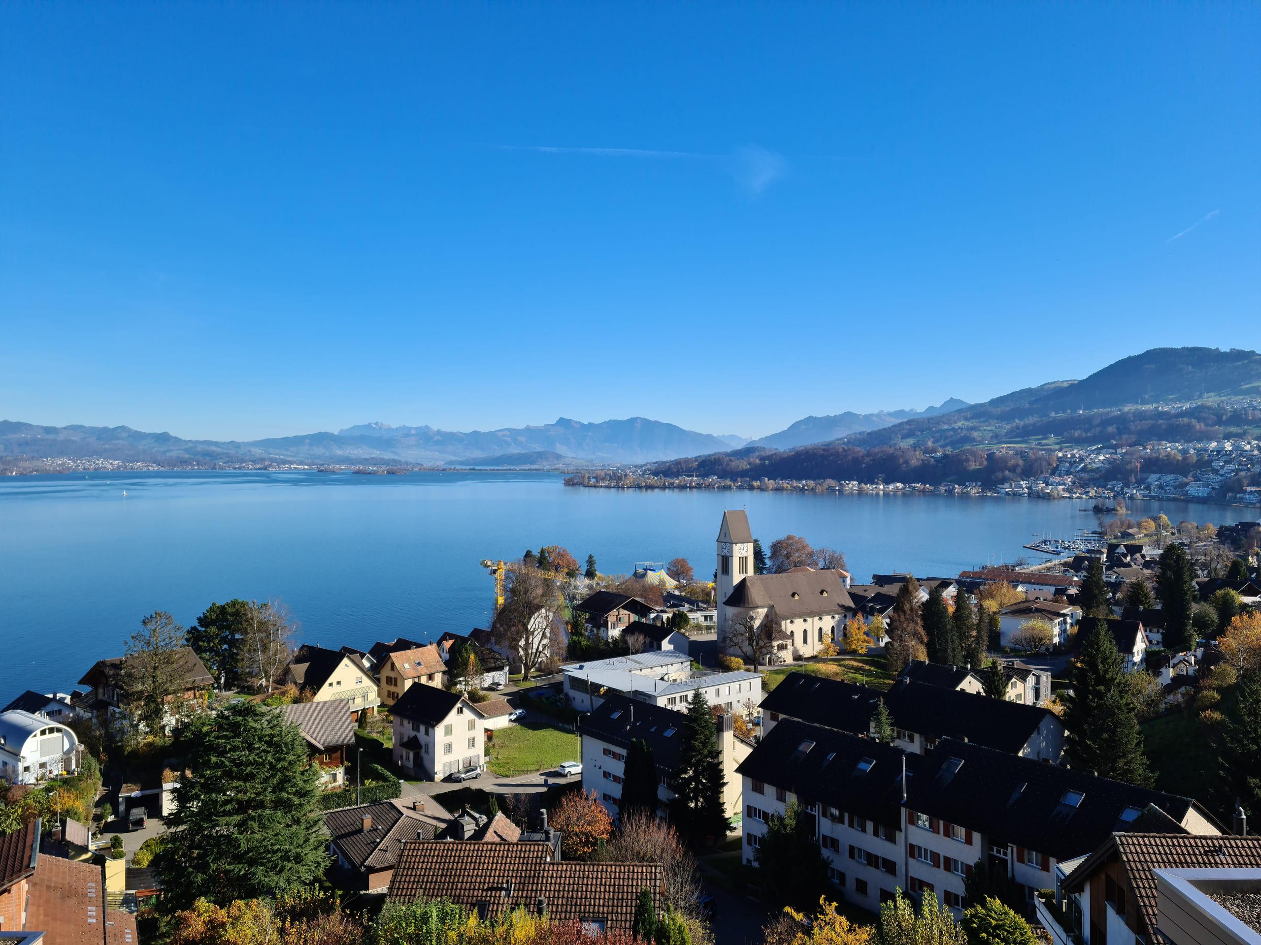 Lake Zurich from above: a village of pitched roofs on the shoreline, the water running blue to the mountains beyond