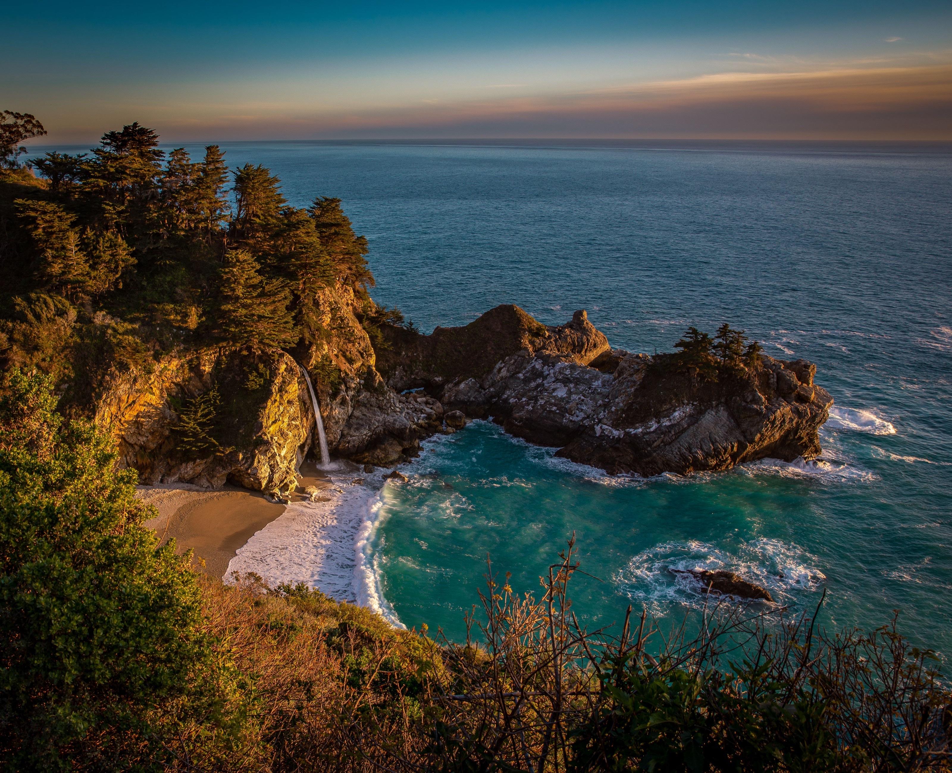 McWay Falls spilling onto a secluded beach in a turquoise cove at dusk, Big Sur, California