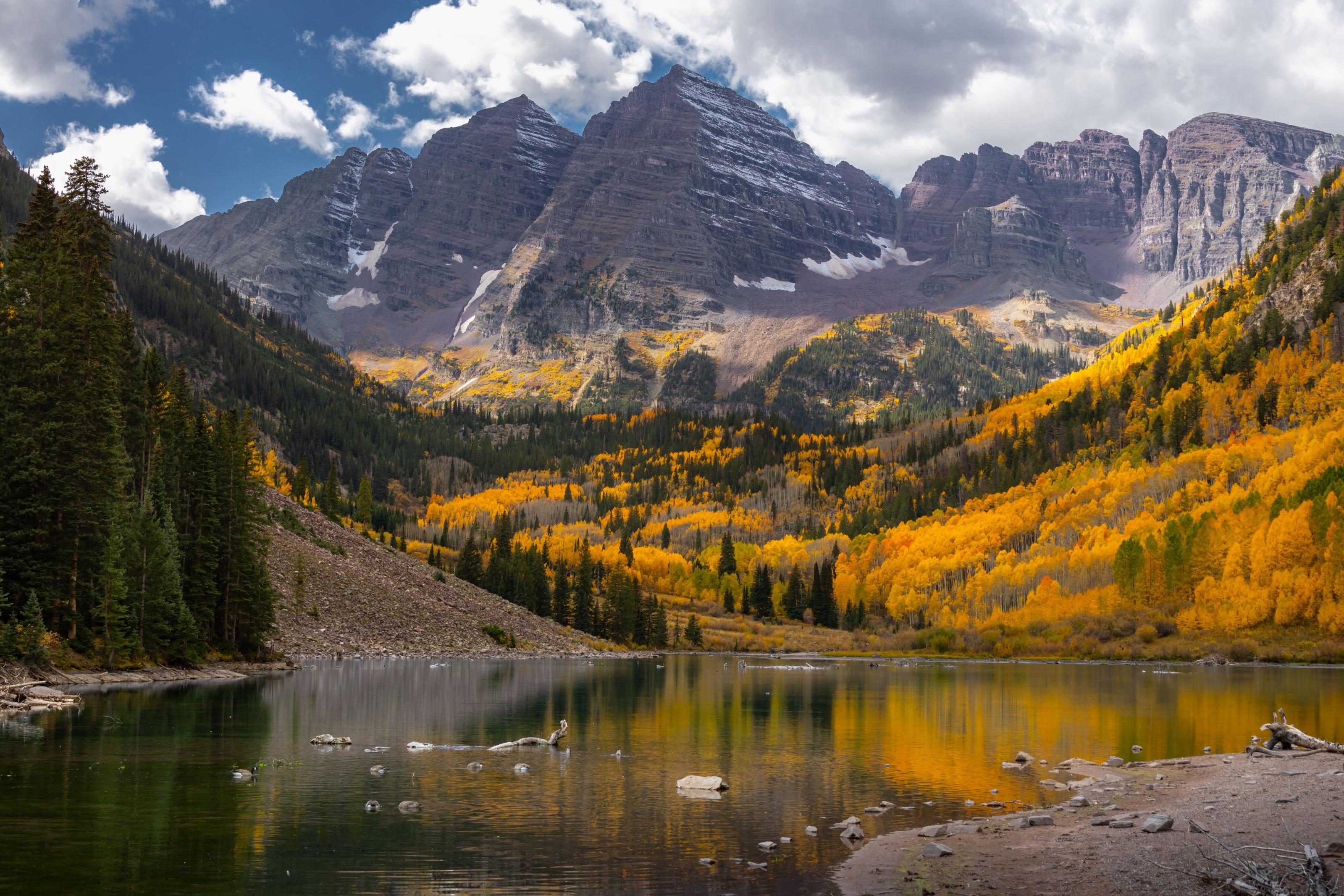 The Maroon Bells rising over Maroon Lake in autumn, golden aspens lining the valley near Aspen, Colorado