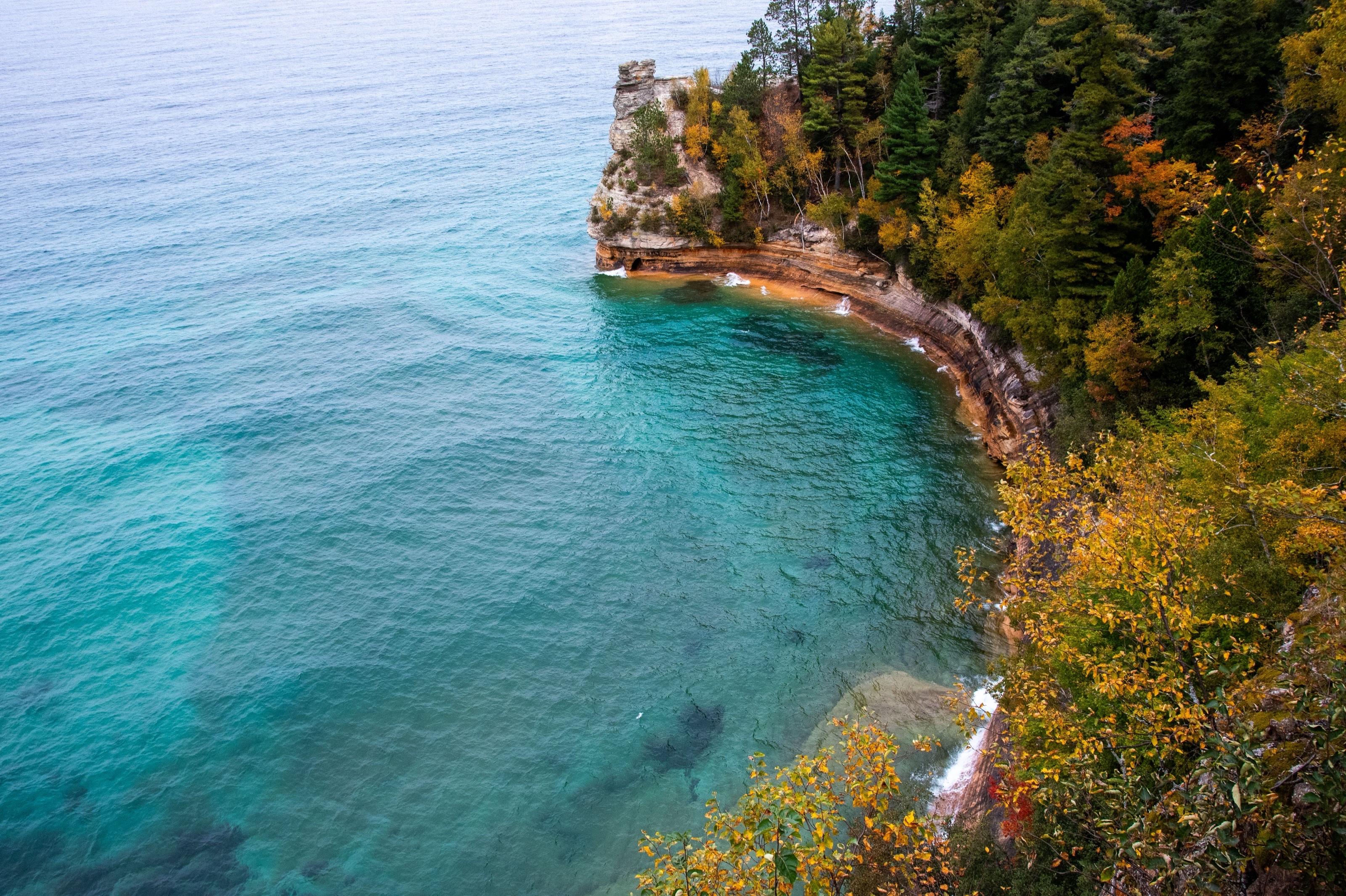 Turquoise Lake Superior cove beneath forested sandstone cliffs at Pictured Rocks near Munising, Michigan