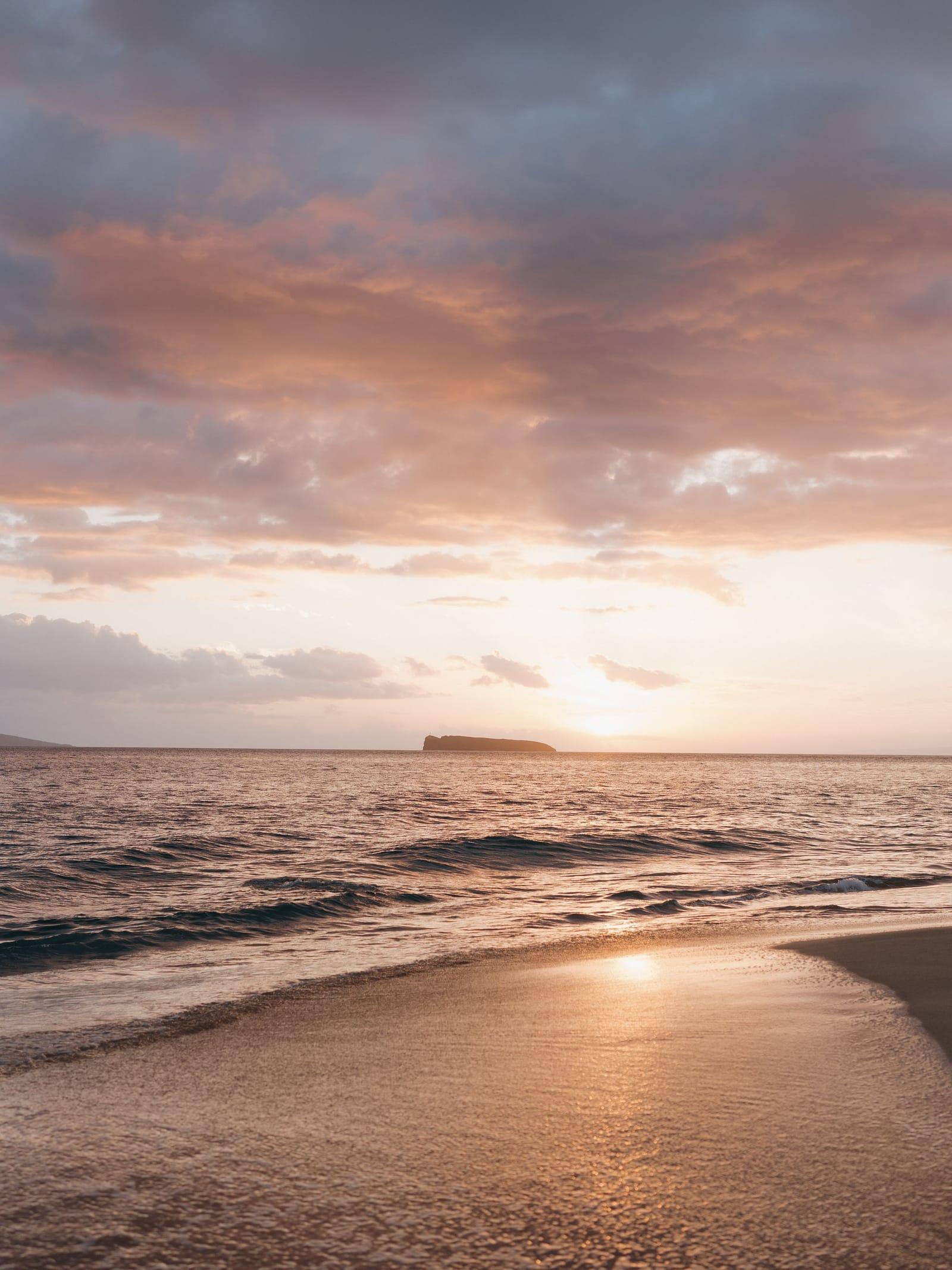 Calm waves and a soft sunset sky over the beach at Kihei