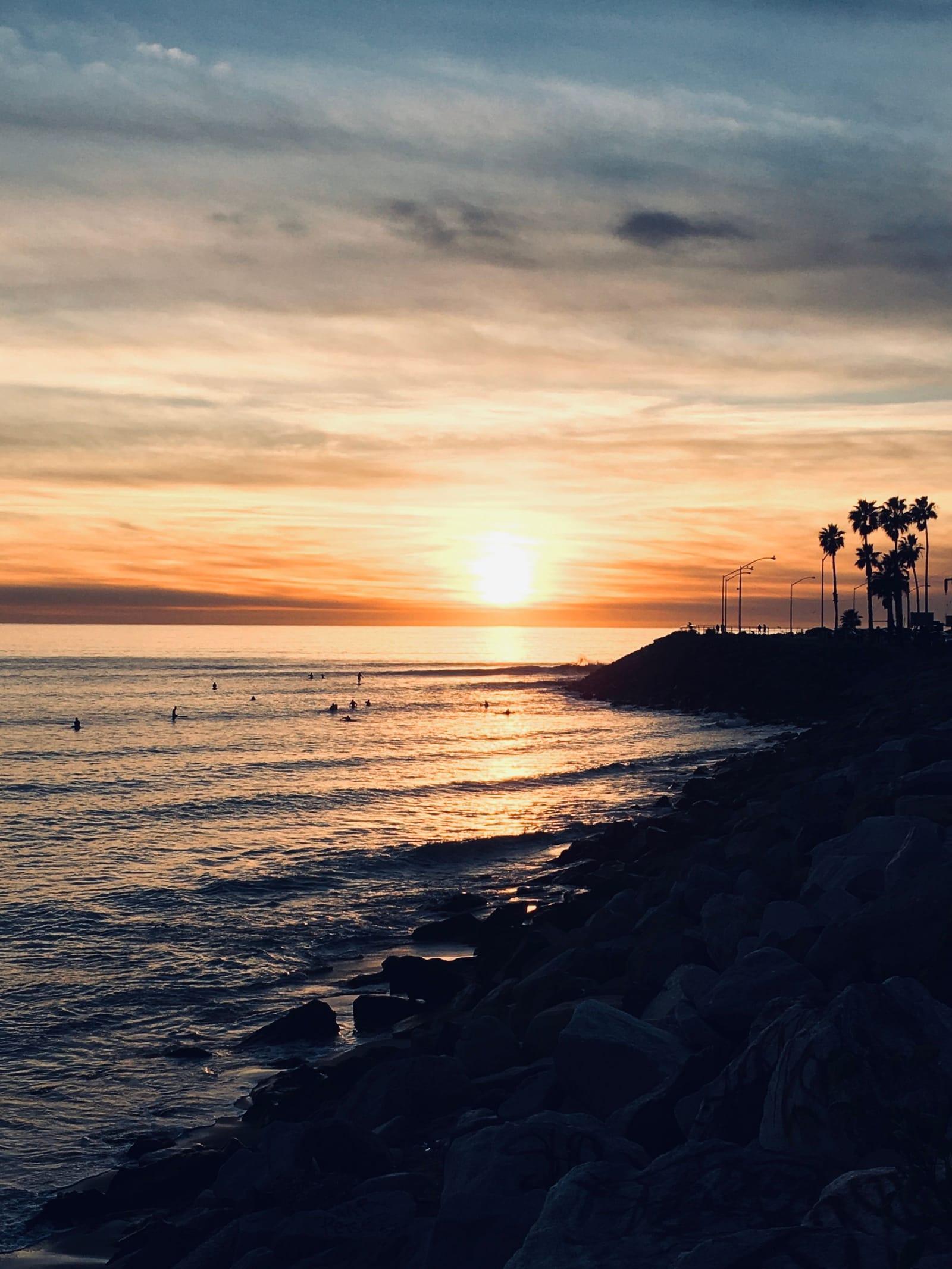 The sun setting over the Pacific beside a palm-lined point