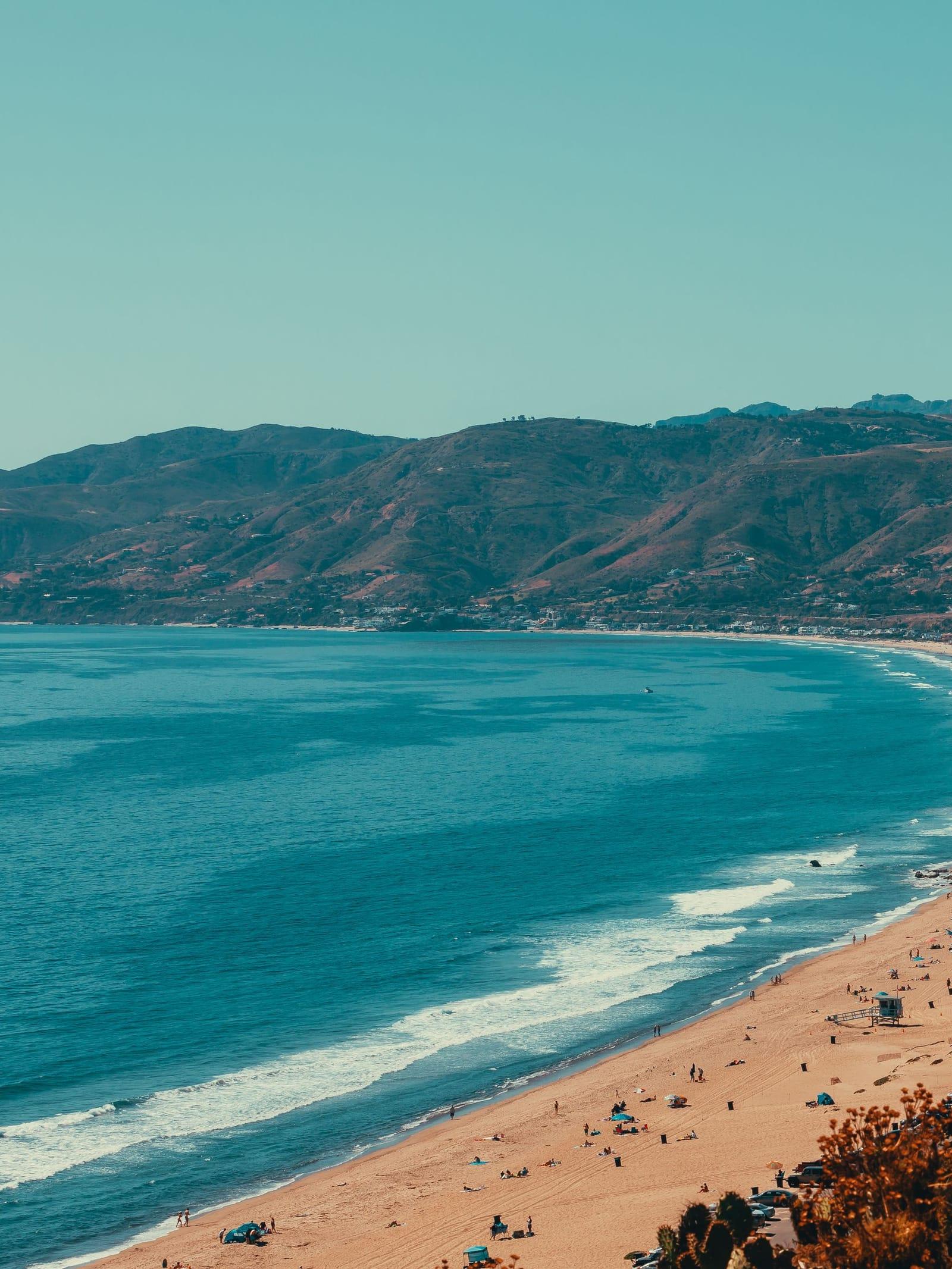 A crescent of beach and turquoise water below the Malibu hills, seen from above