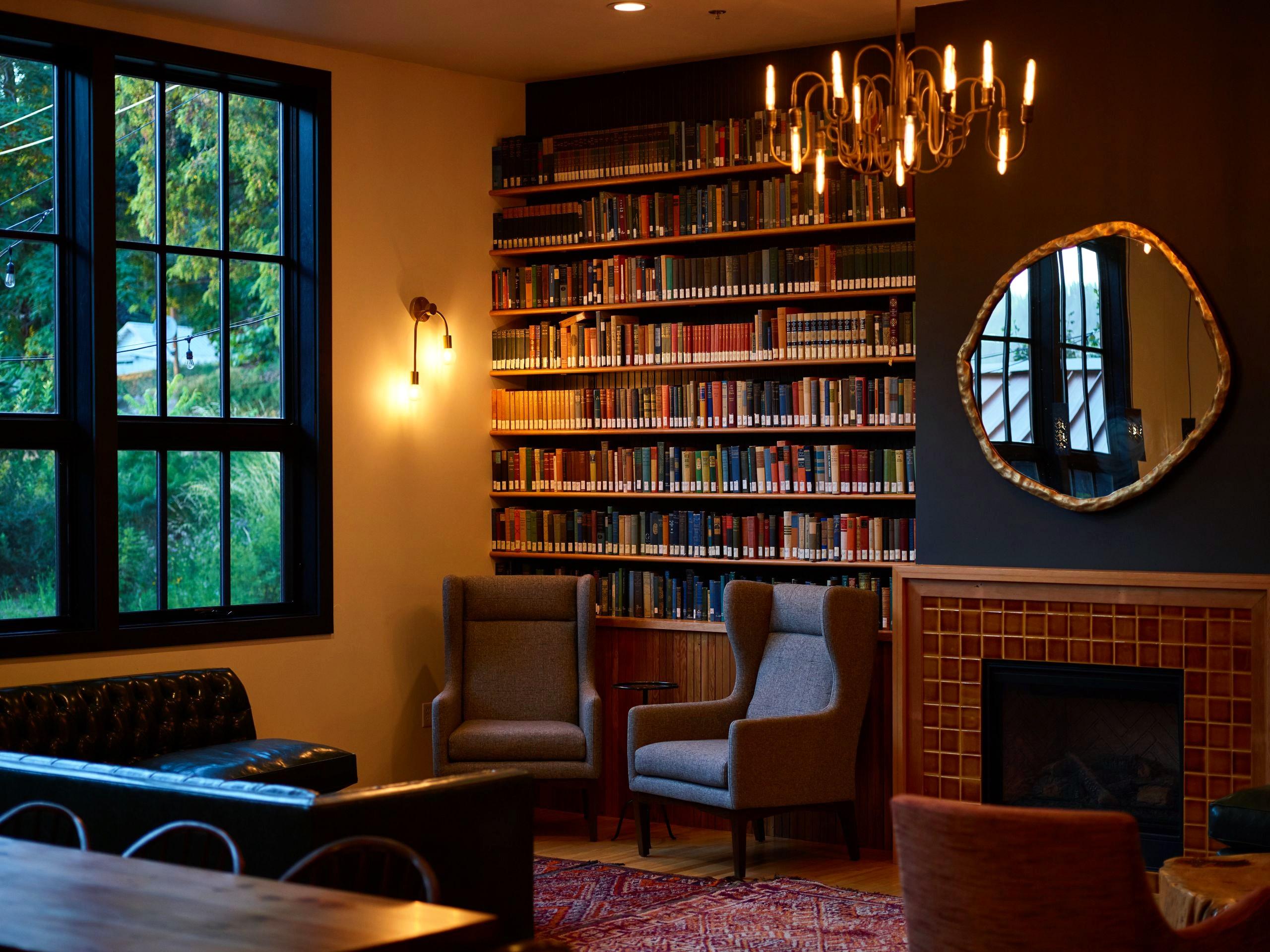 A warm private library with bookshelves, a fireplace, and reading chairs