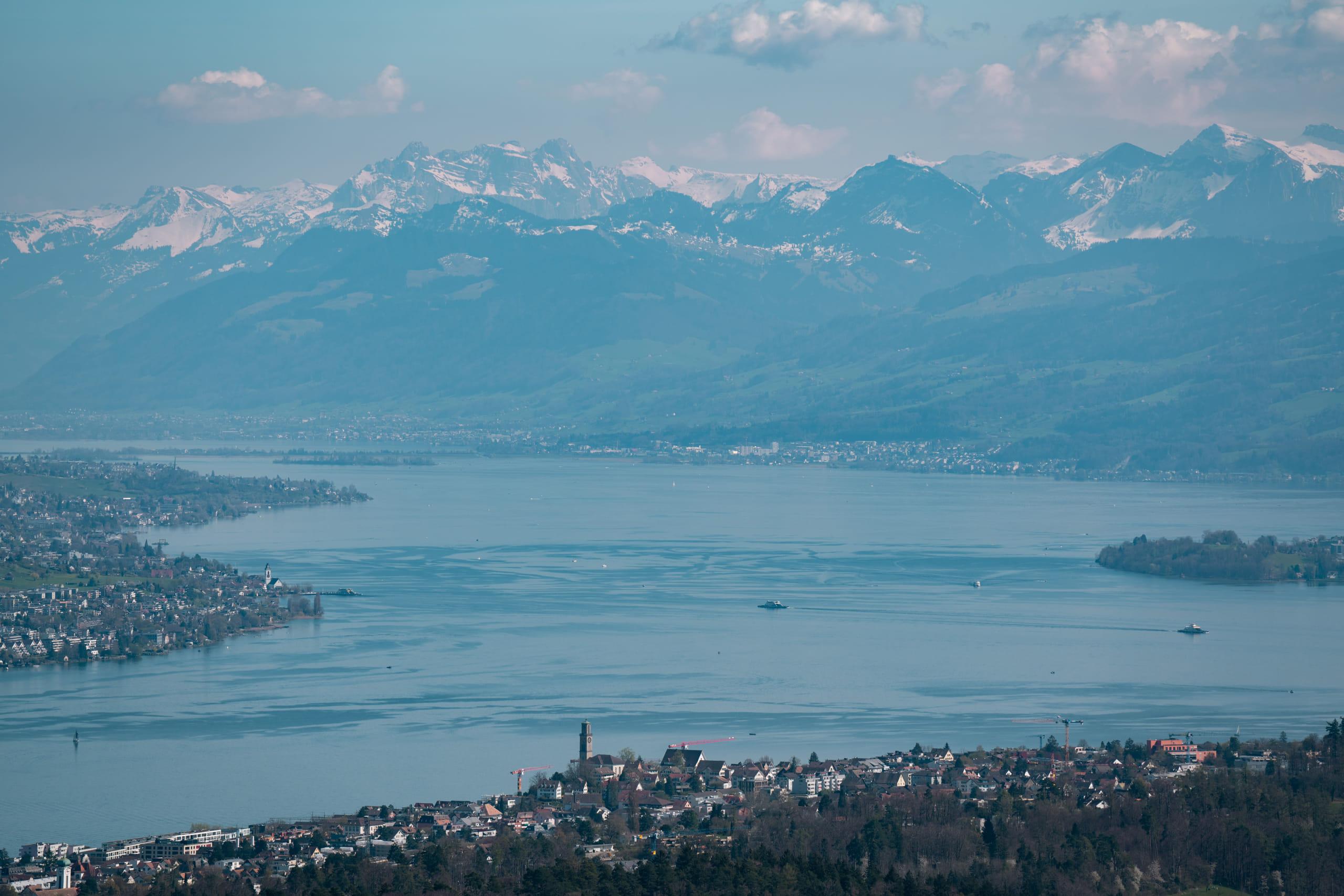A Swiss lake seen from high ground, its shoreline settlements running back towards the snow line of the Alps