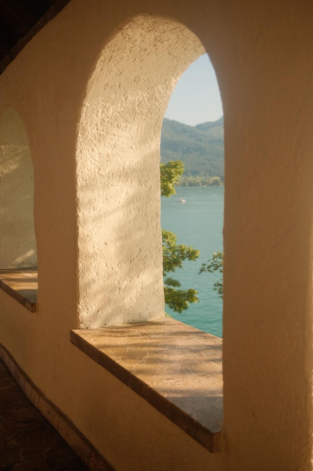 A lake seen through a shaded stone archway, framed and half-hidden