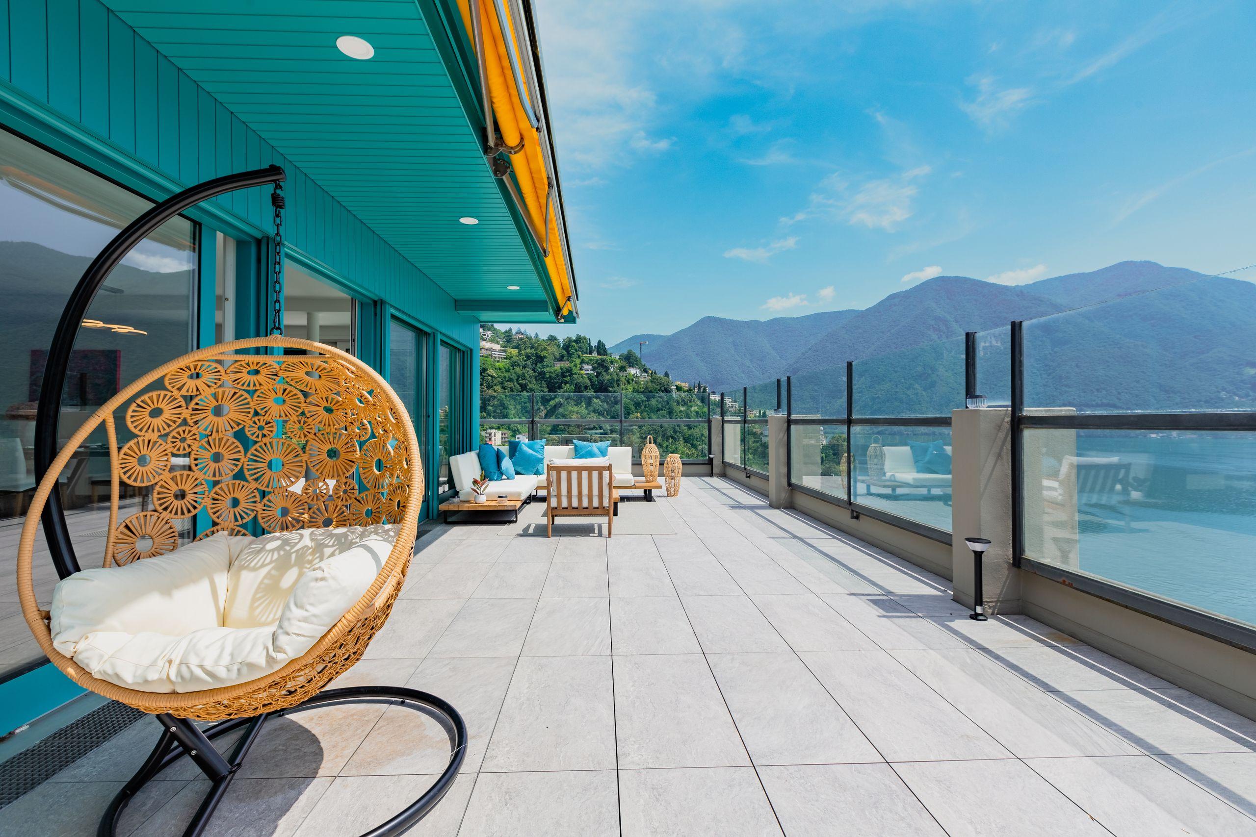 An empty chair on a terrace overlooking a calm mountain lake and alpine landscape