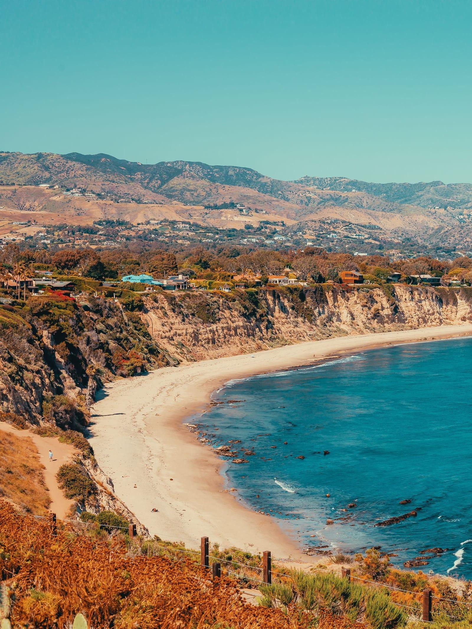A sheltered cove and beach below flowering bluffs in Malibu, seen from above