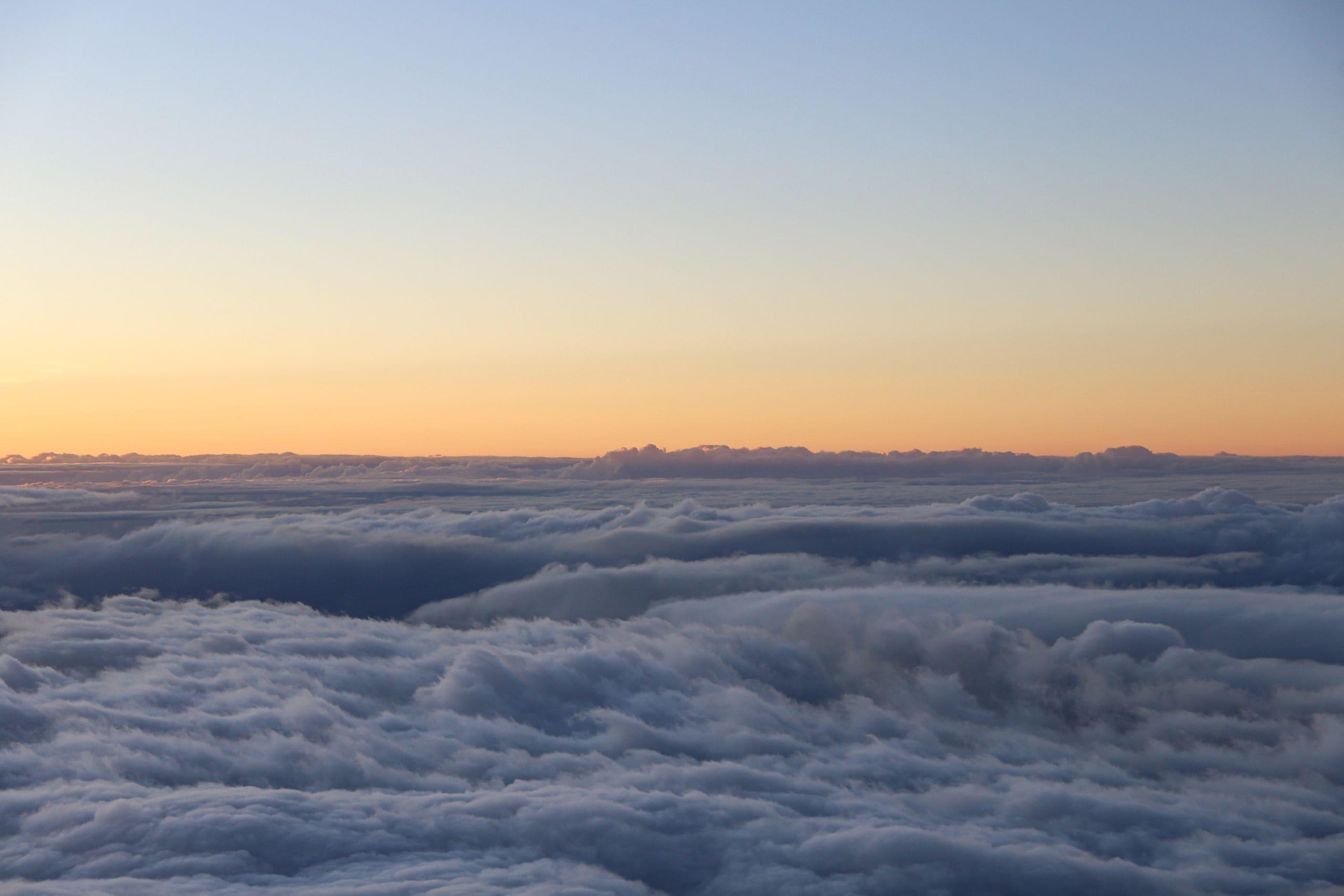 The sun rising over a sea of clouds seen from high on a Hawaiian mountain