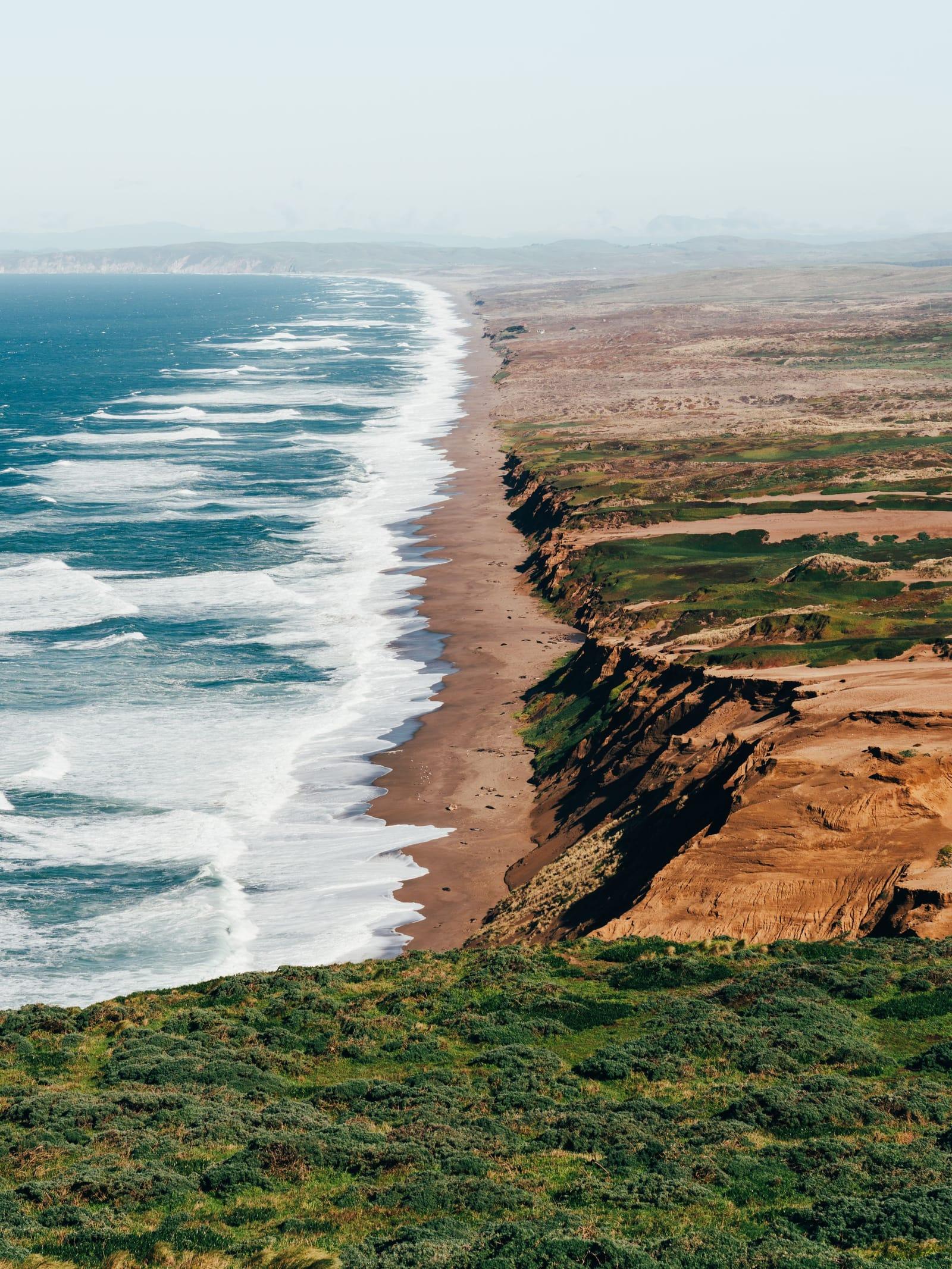 Waves breaking along the long beach below the Point Reyes cliffs on the Northern California coast