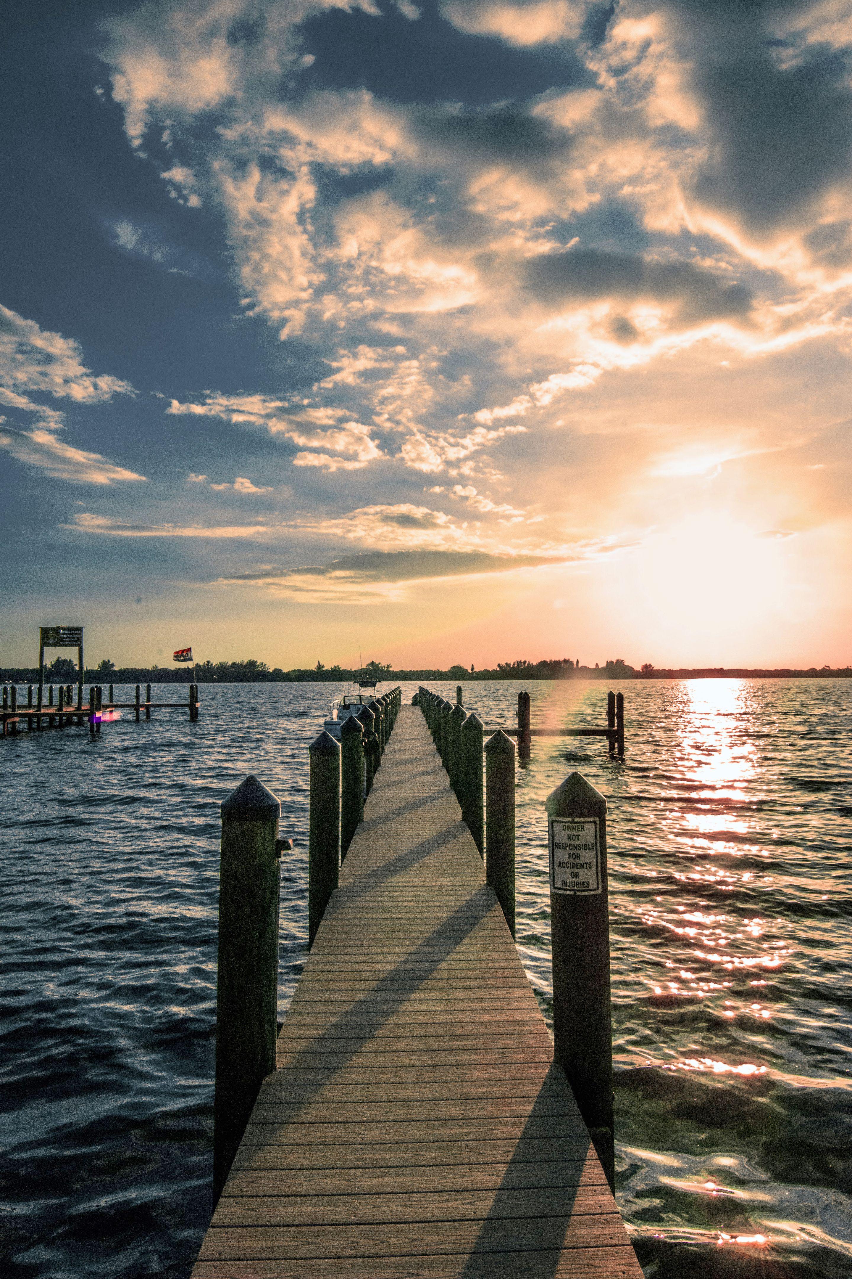 A wooden dock reaching into calm water at sunset in Osprey, Florida