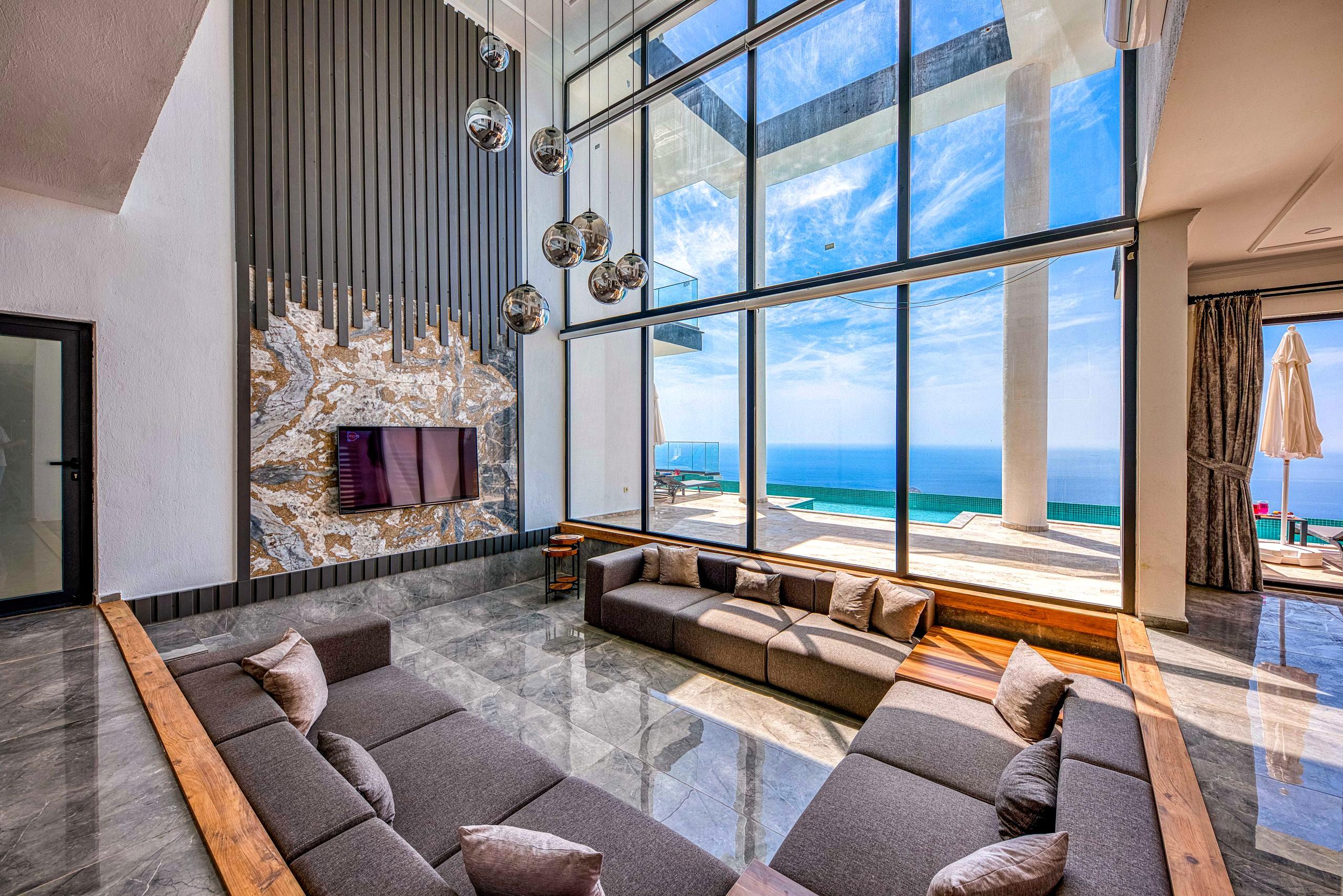 An elegant, light-filled lounge with floor-to-ceiling windows opening onto a calm ocean view