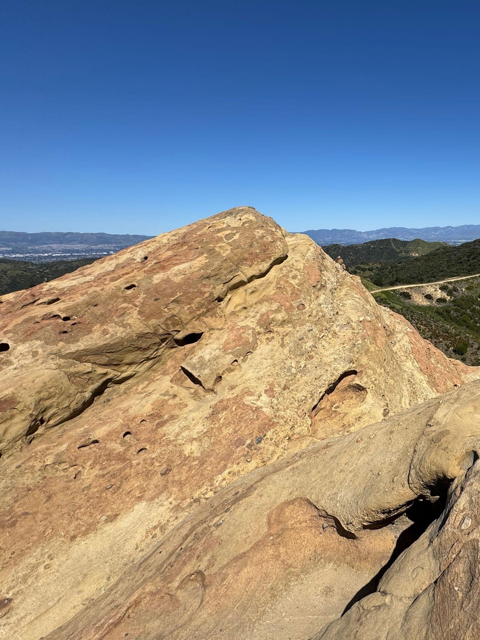 A sandstone boulder on a ridge in the hills above Malibu under a deep blue sky