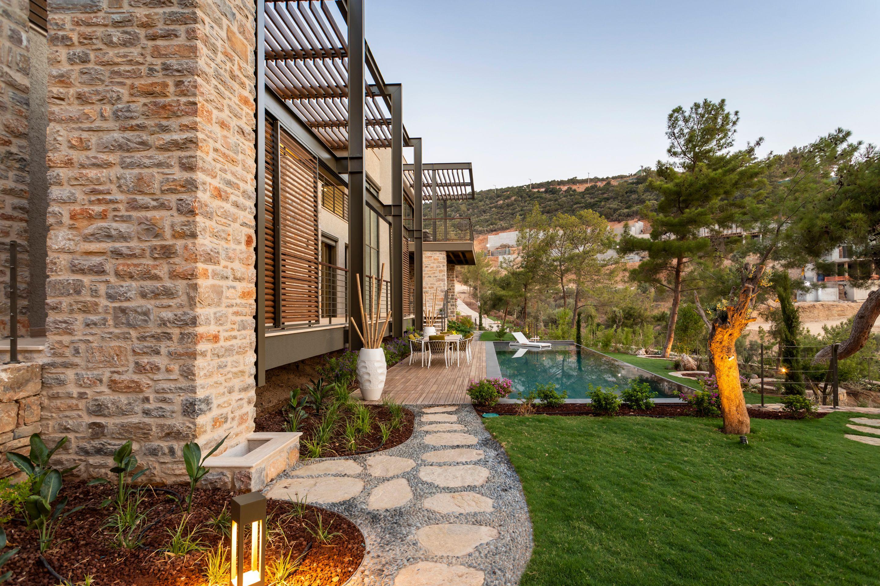A stone villa terrace above a pool, pines and hills beyond in afternoon light