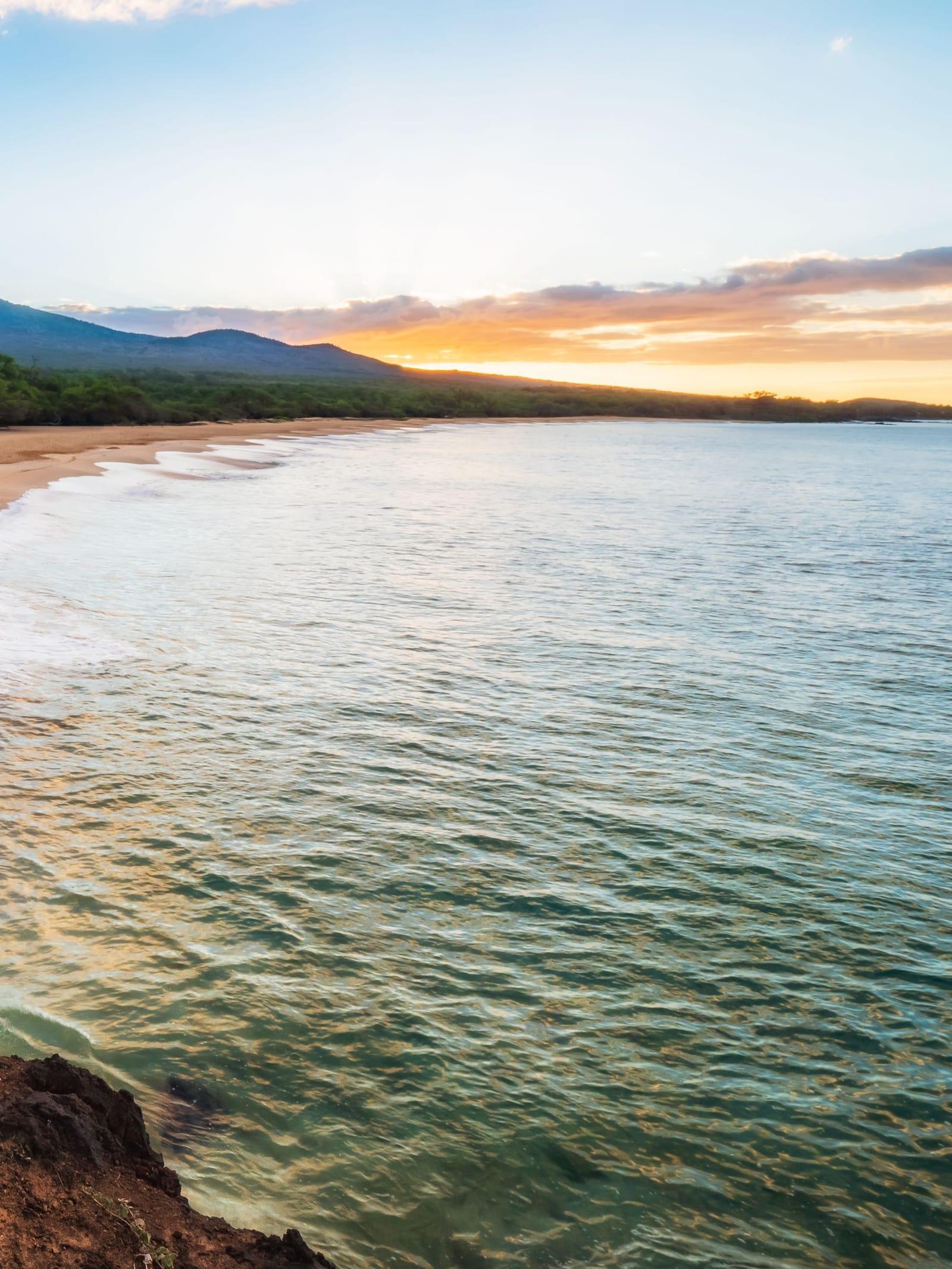 Calm sea and a soft sunrise sky along the shore at Kihei, Maui