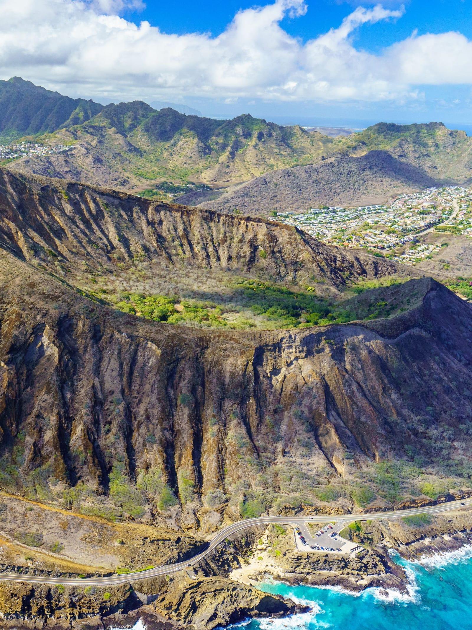 A volcanic crater rising above the coast road and the ocean on Oahu