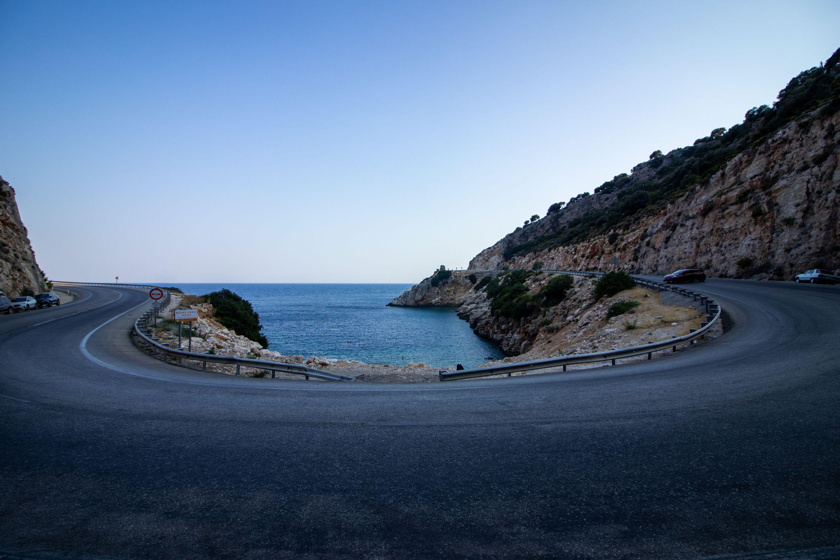 A road curving around a headland above blue sea under a clear sky