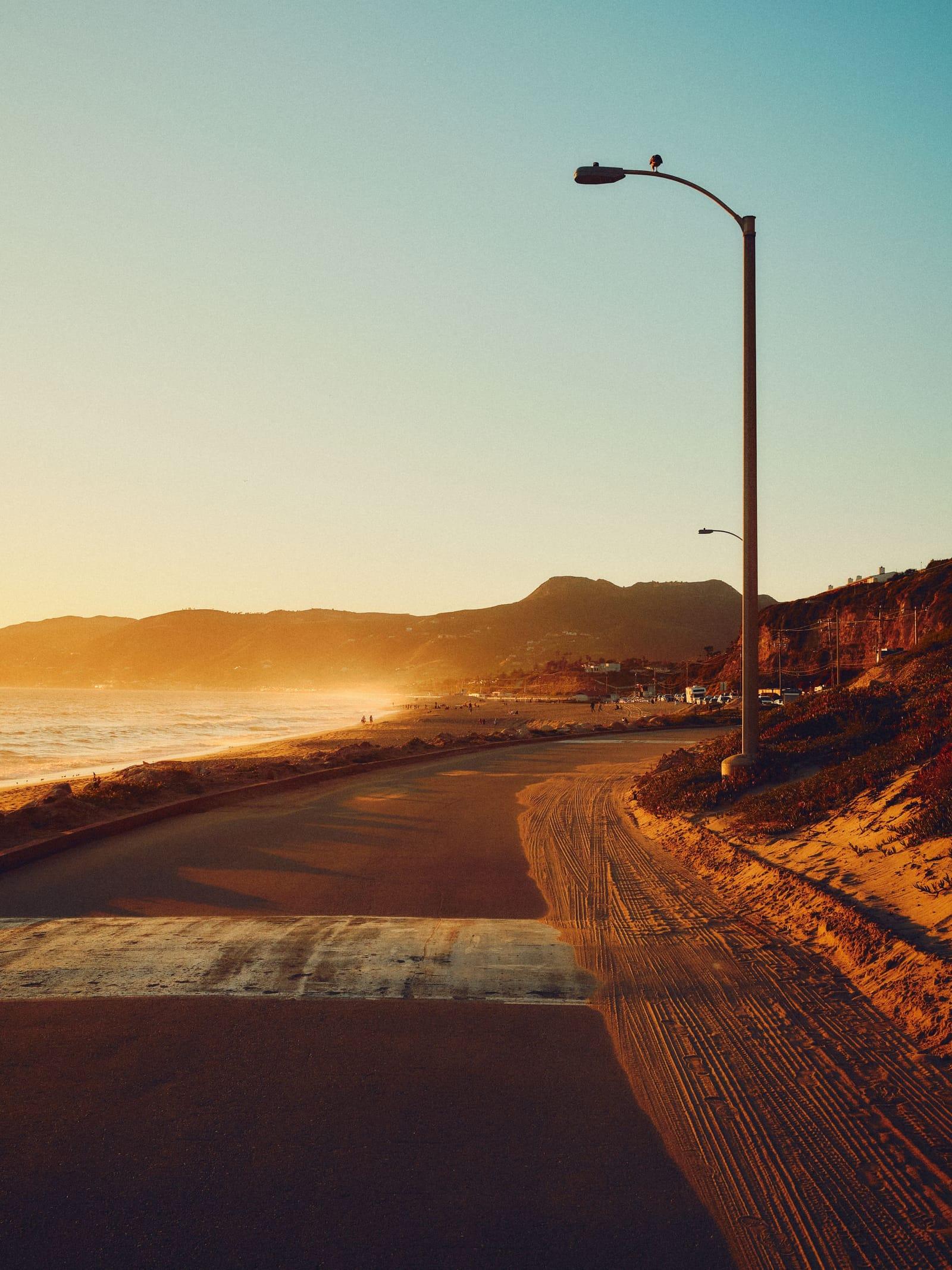 A coastal road near Point Dume at sunset, a streetlight against a clear sky